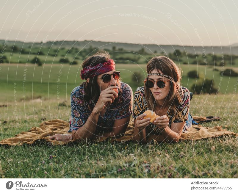 Couple eating while lying down in a meadow woman nature content peeling oranges positive peaceful serene countryside grass lifestyle carefree romantic flower