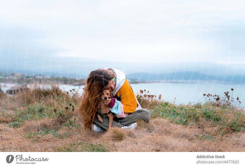 Woman with playful dog in seaside woman kiss face caress beach traveler together smile highland shore hug cathedral beach playa de las catedrales coast female