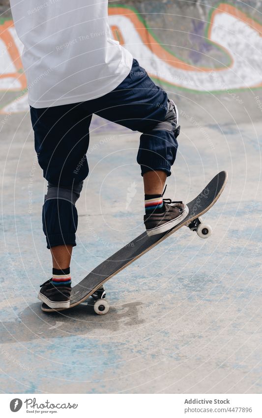 Anonymous young person with skateboard in skate park protect ride training hobby skater extreme motion energy ramp pool active practice activity sport