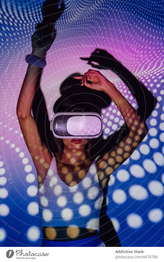 Cool woman exploring virtual reality in goggles in neon lights illumination vr dance projector entertain immerse cool using gadget headset experience technology