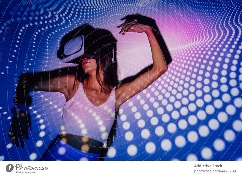 Cool woman exploring virtual reality in goggles in neon lights illumination vr dance projector entertain immerse cool using gadget headset experience technology