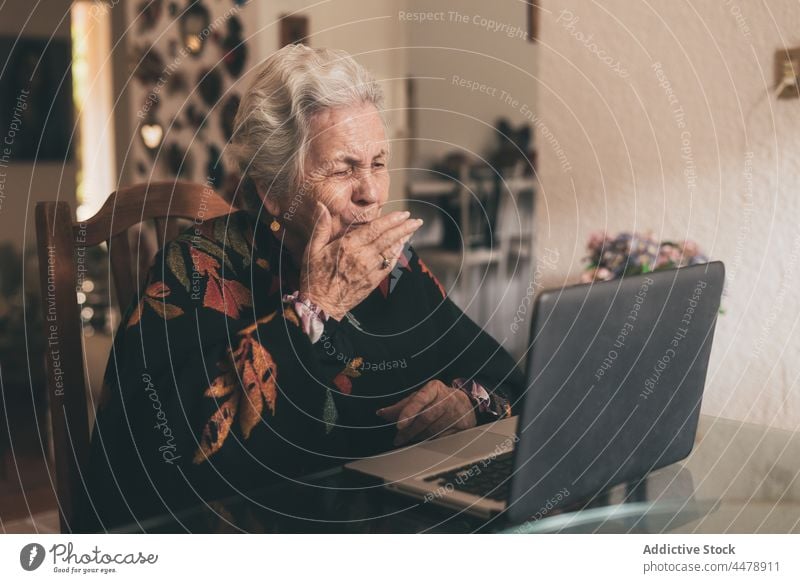 Aged woman talking with relatives at laptop video call positive air kiss communicate conversation internet speak video chat gadget home phone warm clothes