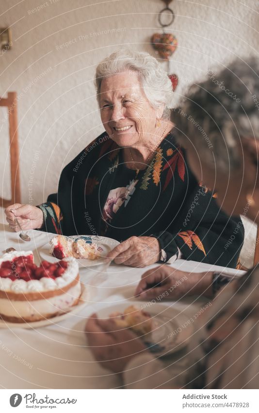 Senior woman with female guest celebrating birthday elderly celebrate cake 90 festive dine pensioner gray hair aged senior event candle holiday delicious happy