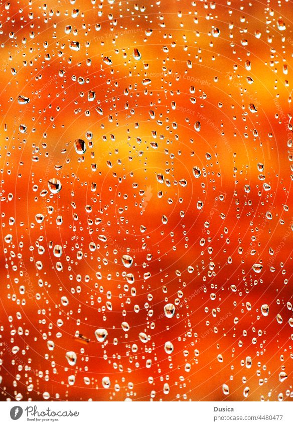 Wet glass with orange and  yellow background wet window rain autumn fall drops droplets water