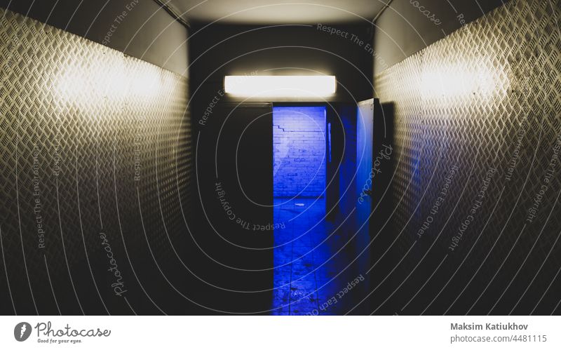 Blue light behind an open door in a mysterious corridor. secret entry blue exit industrial escape steel industry wall metal factory building indoor entrance