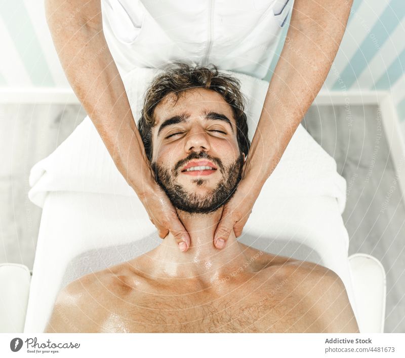 Man with closed eyes getting massage masseur man relax rest shirtless bed lying spa procedure eyes closed serene male tranquil beard comfort recreation pleasure