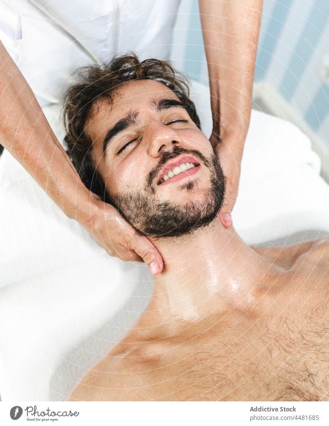 Man with closed eyes getting massage masseur man relax rest shirtless bed lying spa procedure eyes closed serene male tranquil beard comfort recreation pleasure