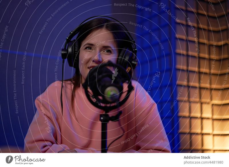 Woman recording podcast in studio woman smile sound microphone radio host colleague together headphones female young casual headset broadcast work positive