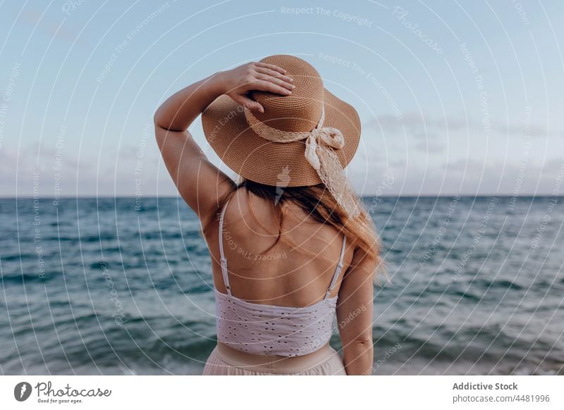 Unrecognizable woman in dress and hat summer beach sea coast water shore nature female admire picturesque seaside sky daytime daylight scenery harmony ripple