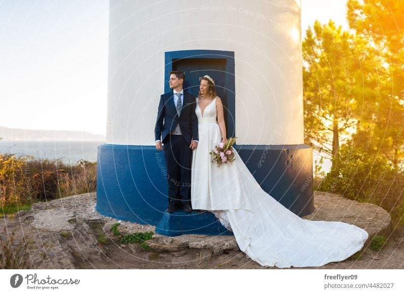 Just married couple on the door of a lighthouse wedding husband wife apparel love celebration copy space heterosexual bride groom forest tree sunset portrait