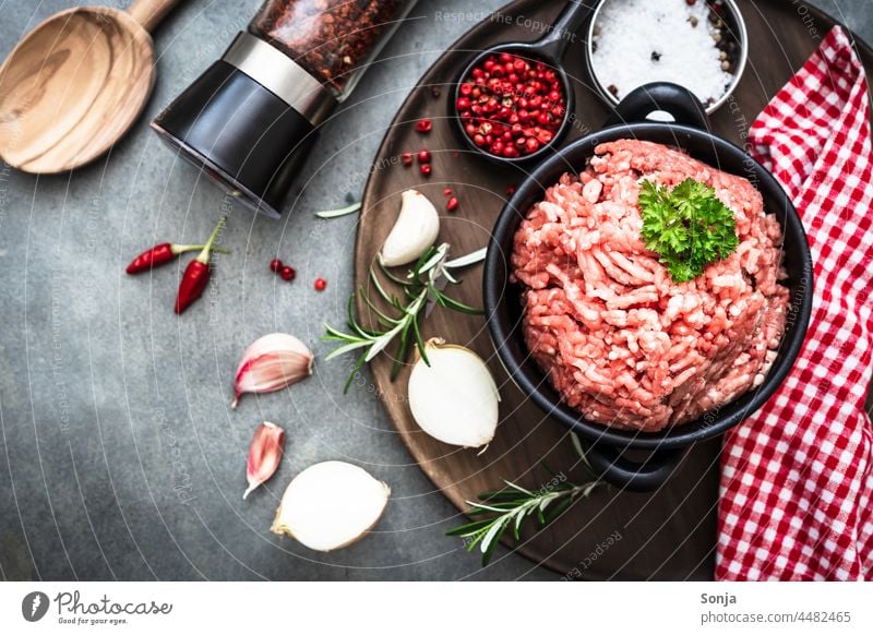 Raw minced meat in a pot and ingredients on a gray table Minced meat Preparation seasoning Pepper mill Cooking Kitchen Ingredients Healthy Fresh background