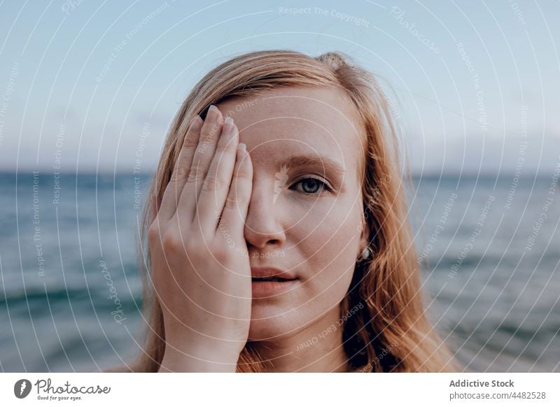 Young woman covering face with hand summer seashore evening calm portrait nature water sunset female peaceful beach young coast hide seaside dusk tender