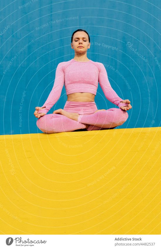 Calm woman sitting and meditating lotus pose calm meditate wellness harmony activewear peaceful practice zen female yoga relax healthy young asana exercise