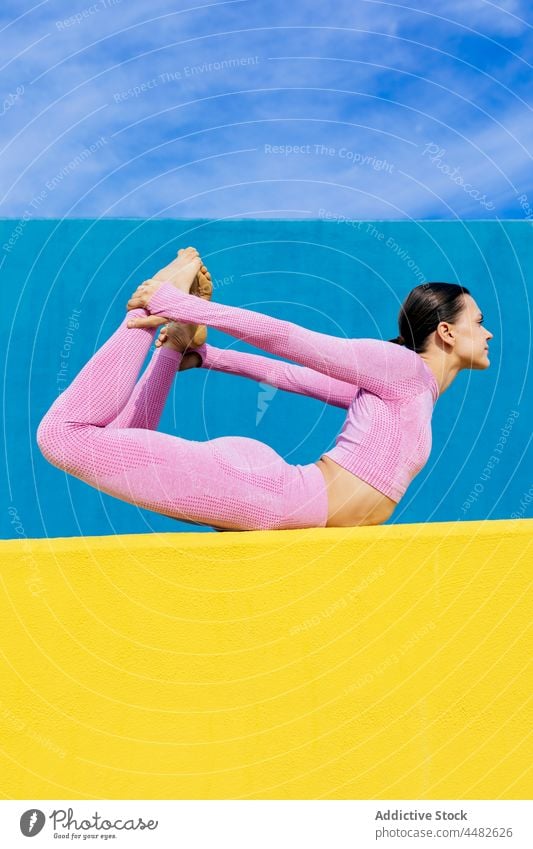 Flexible woman performing Bow pose on mat practice yoga training bow stretch dhanurasana balance concentrate sportswear position wellbeing harmony healthy