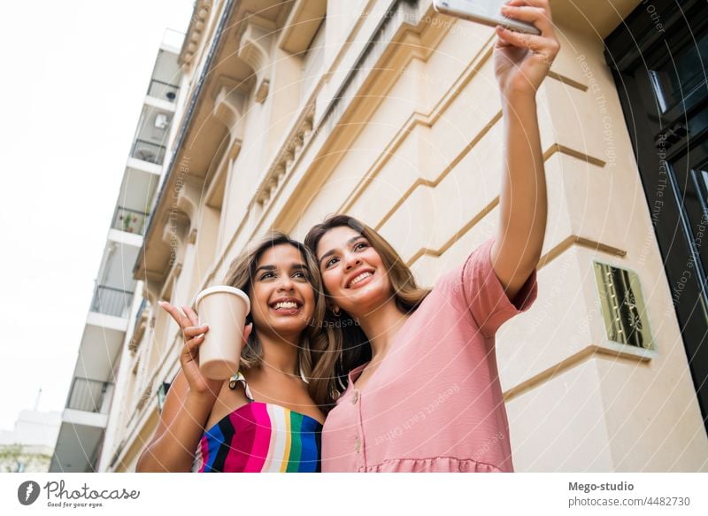 Two friends taking selfie with phone outdoors. two mobile smiling laughing young friendship lifestyle leisure talking fun women cellular selfies app enjoying