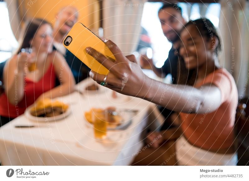 Group of friends taking a selfie with a mobile phone at a restaurant. together drink beer food meal friendship indoors enjoyment smartphone social media happy