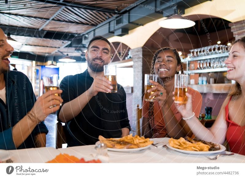 Group of friends enjoying a meal together at a restaurant. drink beer bar friendship indoors enjoyment fun young happy alcohol lifestyle smiling social drinking