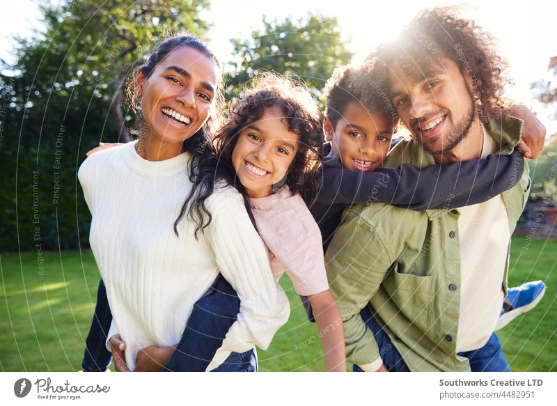 Portrait of family in garden smiling towards camera portrait mixed race asian smile looking at camera son mother father outdoors day four people authentic