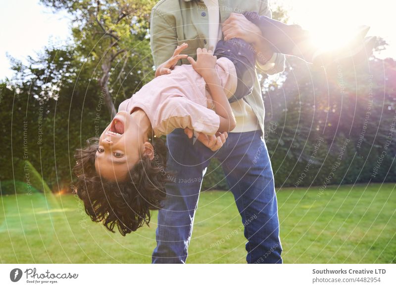 Boy being held upsidedown in garden with mouth open mixed race boy hold smile child fun outdoors day two people portrait authentic childhood lifestyle happy