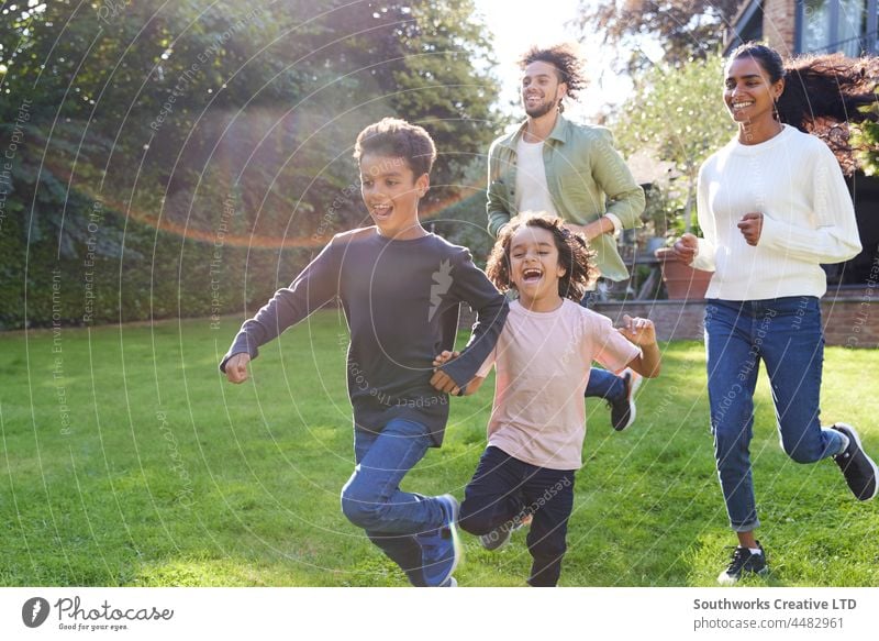 Family running on lawn outside house mixed race asian family boy mother father son brother outdoors day four people portrait authentic childhood lifestyle happy