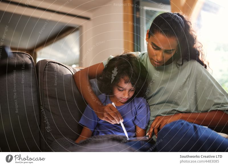 Mother and son using tablet on sofa mixed race asian mother relax leisure bonding together indoors day home interior two people portrait authentic childhood