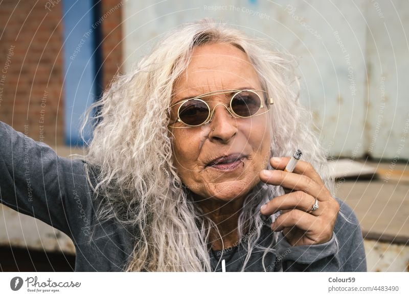 Woman blowing the smoke of a cigarette smile old woman fashionable friendly stylish stop smoking smoking woman elderly female one lifestyle senior caucasian