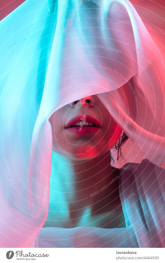 Studio portrait of woman with her eyes covered in neon blue and red lightning cloth model artistic dark alone hipster cool stylish retro bright night studio