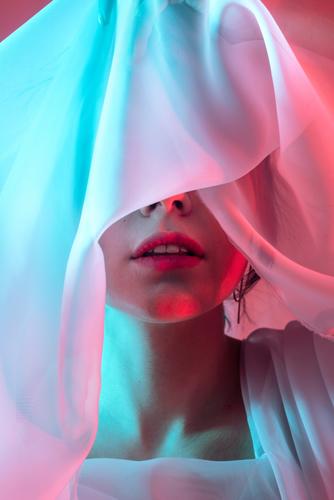 Studio portrait of woman with her eyes covered in neon blue and red lightning cloth model artistic dark alone hipster cool stylish retro bright night studio