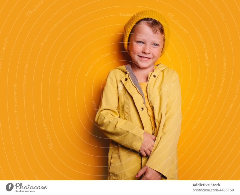 Laughing boy looking away against yellow background happy laugh cheerful autumn portrait jacket outerwear beanie glad joy style kid trendy child bright outfit