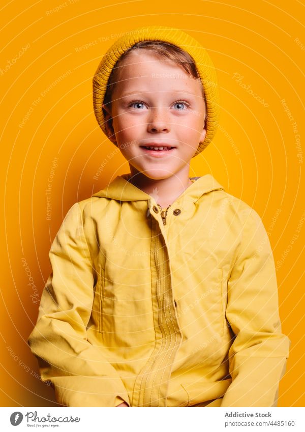 Laughing boy looking at camera against yellow background happy laugh cheerful autumn portrait jacket outerwear beanie glad joy style kid trendy child bright