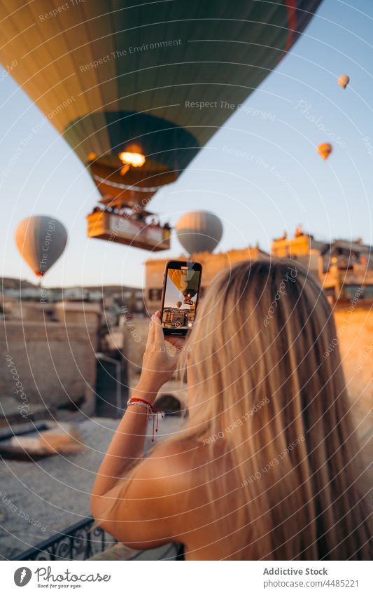 Woman taking picture of hot air balloons woman cellphone smartphone take photo shoot gadget using blogger memory female fence mobile moment photographer weekend
