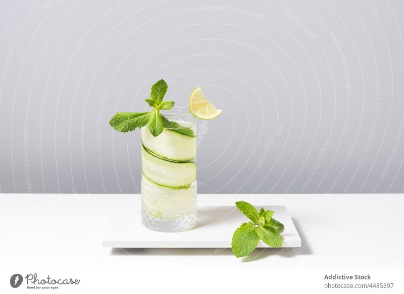 Refreshing cocktail with lime and cucumber served on white table gin tonic citrus alcohol mint beverage fruit cool ingredient delicious sour sunlight aperitif
