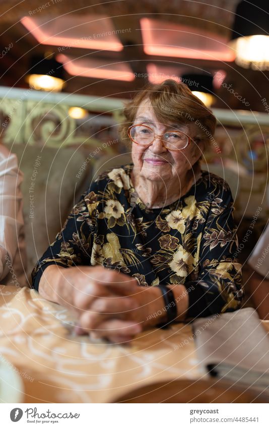 Elderly woman at the restaurant senior elderly portrait aged glasses retired dinner happy enjoy female smiling clasp hand cafe table granny lunch cheerful