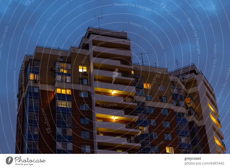 High-rise apartment house in the dusk residential building apartment block dwelling evening highrise window light multistory high-rise flat exterior