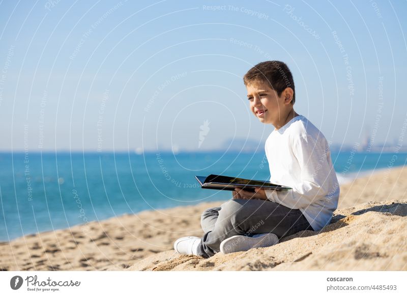 Little kid reading a book on the beach activity adorable autumn back boy caucasian child childhood city coast creative curious cute day holiday jeans keen learn