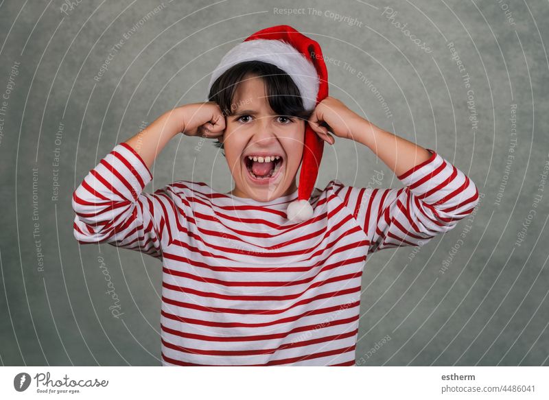Angry kid wearing Santa Claus hat with his hands on his head child christmas santa claus angry screaming desperate christmas eve furious crazy stressed nervous