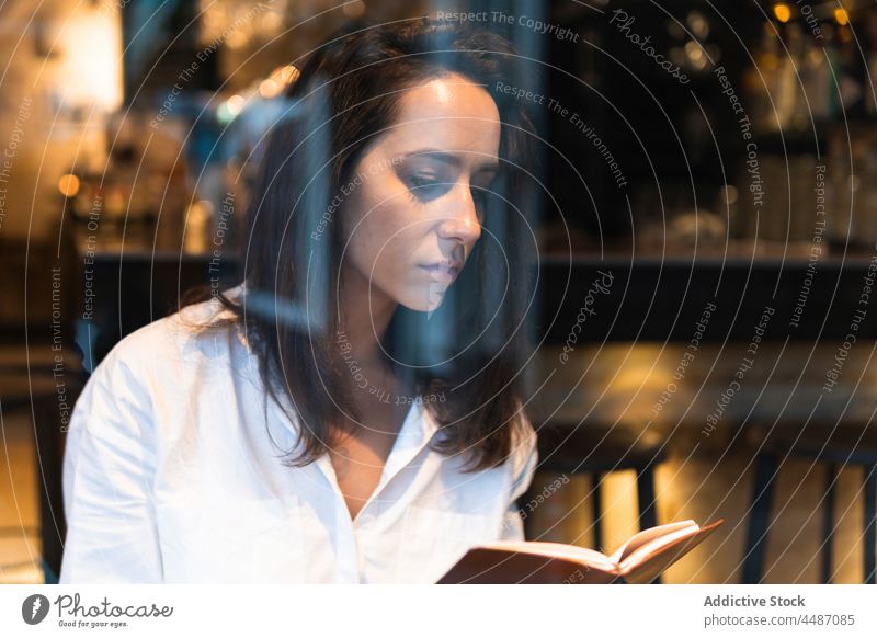 Thoughtful woman reading book in cafe concentrate knowledge hobby learn focus serious education female young literature study thoughtful pensive calm sit smart
