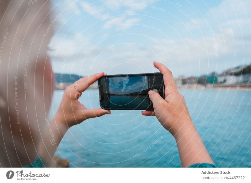 Female taking photo of picturesque seascape in daytime woman smartphone take photo device ocean memory style cityscape bay photography female donostia