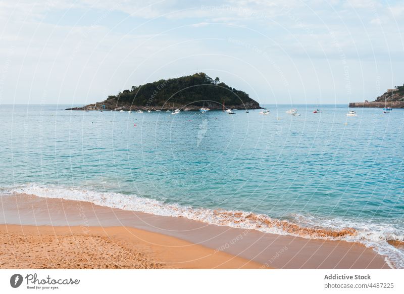 Sandy beach washing by calm water of ocean nature island coast scenery picturesque shore sea san sebastian spain donostia basque country bay of biscay landscape