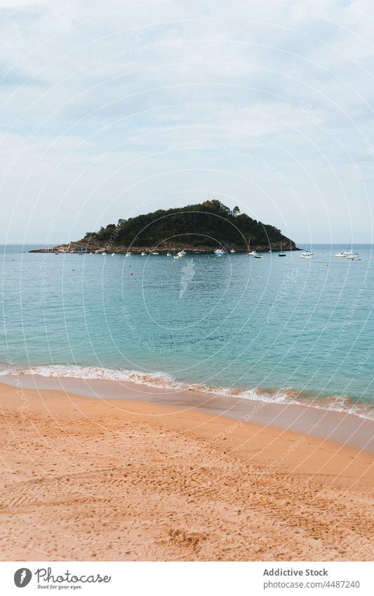 Sandy beach washing by calm water of ocean nature island coast scenery picturesque shore sea san sebastian spain donostia basque country bay of biscay landscape