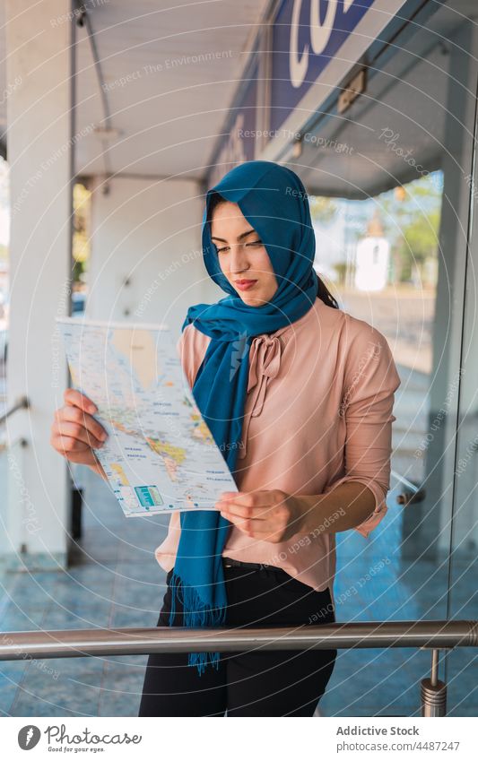 Arab woman reading paper map in city navigate orientate tourist hijab headscarf street female muslim arab ethnic culture tradition travel tourism lost guide