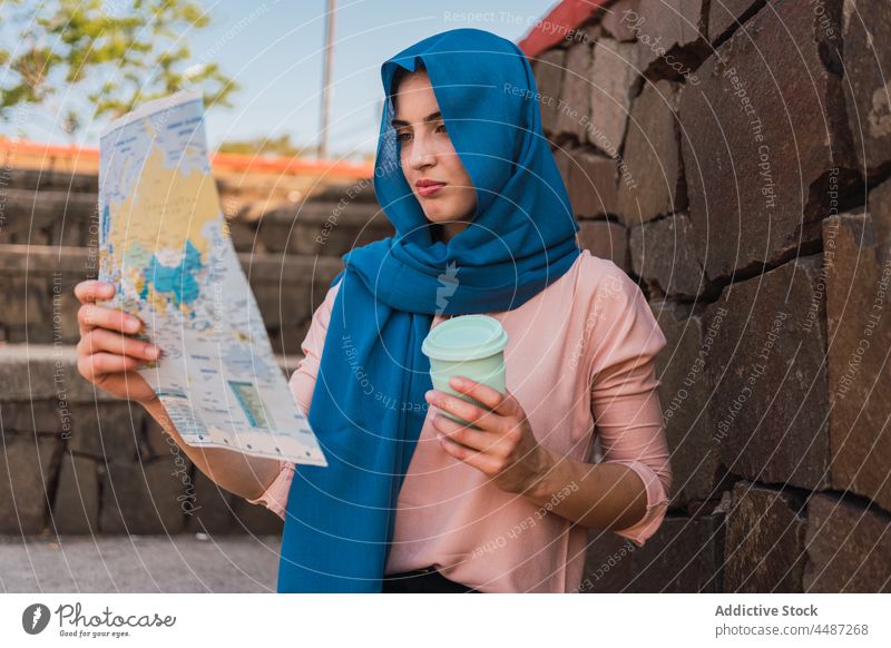 Arab woman navigating with paper map read navigate search guide city orientate headscarf hijab female ethnic arab muslim focus coffee concentrate destination