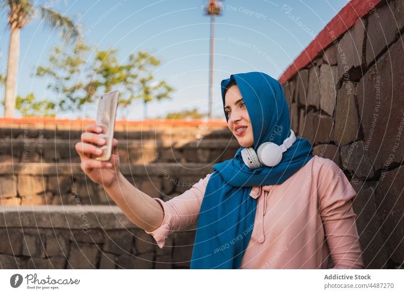 Arab woman in hijab taking selfie in city headscarf smartphone self portrait moment charming tradition female arab ethnic muslim street device culture using