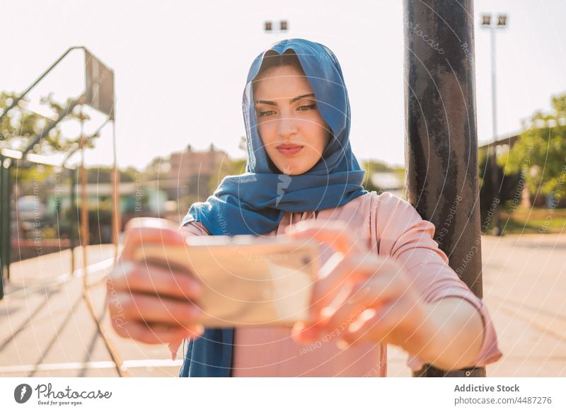 Arab woman in hijab taking selfie in city headscarf smartphone self portrait moment charming tradition female arab ethnic muslim street device culture using