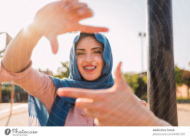 Muslim woman showing framing gesture frame sign photo symbol headscarf hijab smile female ethnic arab muslim positive glad happy optimist pretend take photo