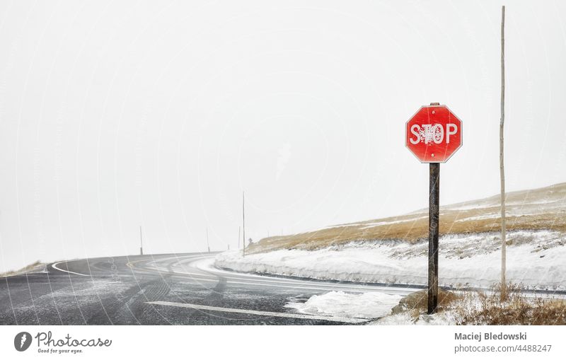 Stop sign at a mountain roads intersection during blizzard, selective focus, Colorado, USA. stop traffic mountains snow drive danger trip highway adventure