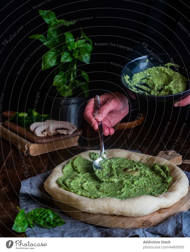 Cook making pizza with pesto sauce cook add prepare green delicious basil food cuisine tasty kitchen chef gourmet italian cuisine culinary homemade table dark