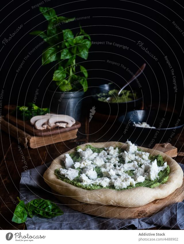 Uncooked pizza with pesto sauce and cheese vegetarian uncooked whole table italian food basil mozzarella meal delicious green gourmet homemade tasty leaf herb