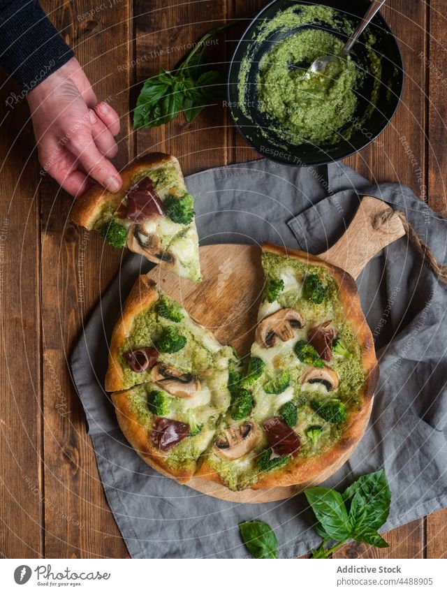 Crop person with slice of vegetarian pizza pesto sauce mushroom broccoli piece table tasty delicious cuisine serve meal gourmet food gastronomy take champignon