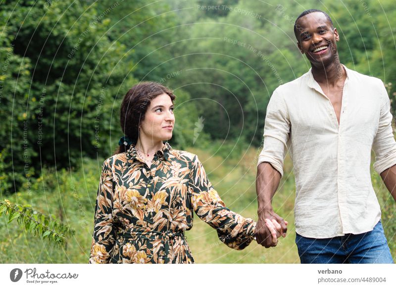 diverse ethnics couple holding hads walking in a park in fall afro caucasian love family new order culture woman people smiling outdoors smile happiness summer